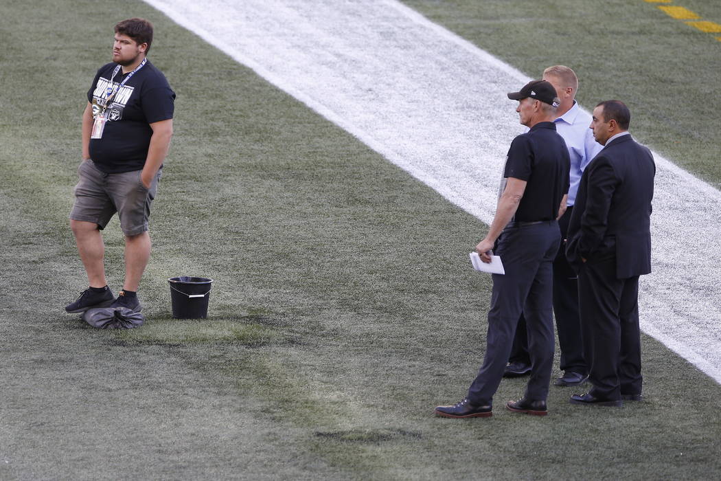 Officials assess the location where the CFL goal post holes were, before an NFL preseason footb ...