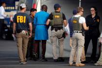 Federal agents hold a detainee, second from left, at a downtown Los Angeles parking lot after p ...