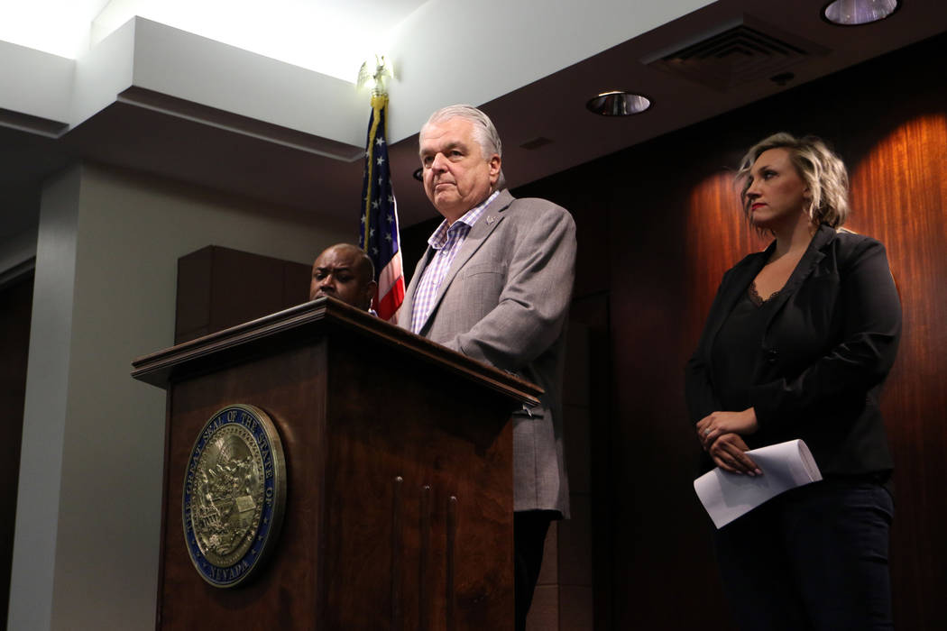 Gov. Steve Sisolak, center, takes questions during a news conference at the Grant Sawyer State ...