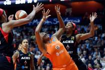 Connecticut Sun forward Morgan Tuck, center, is fouled by Las Vegas Aces guard Sydney Colson, r ...