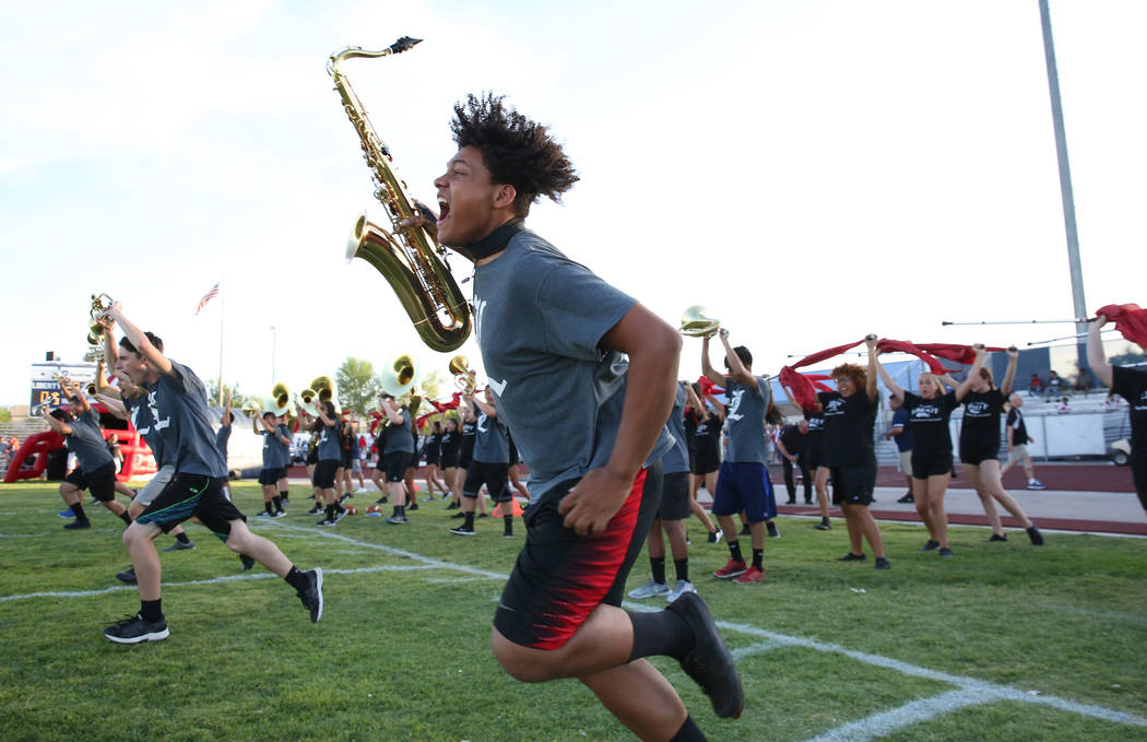 Member of the Liberty High marching band Damien Alexander, front, take the field during a footb ...