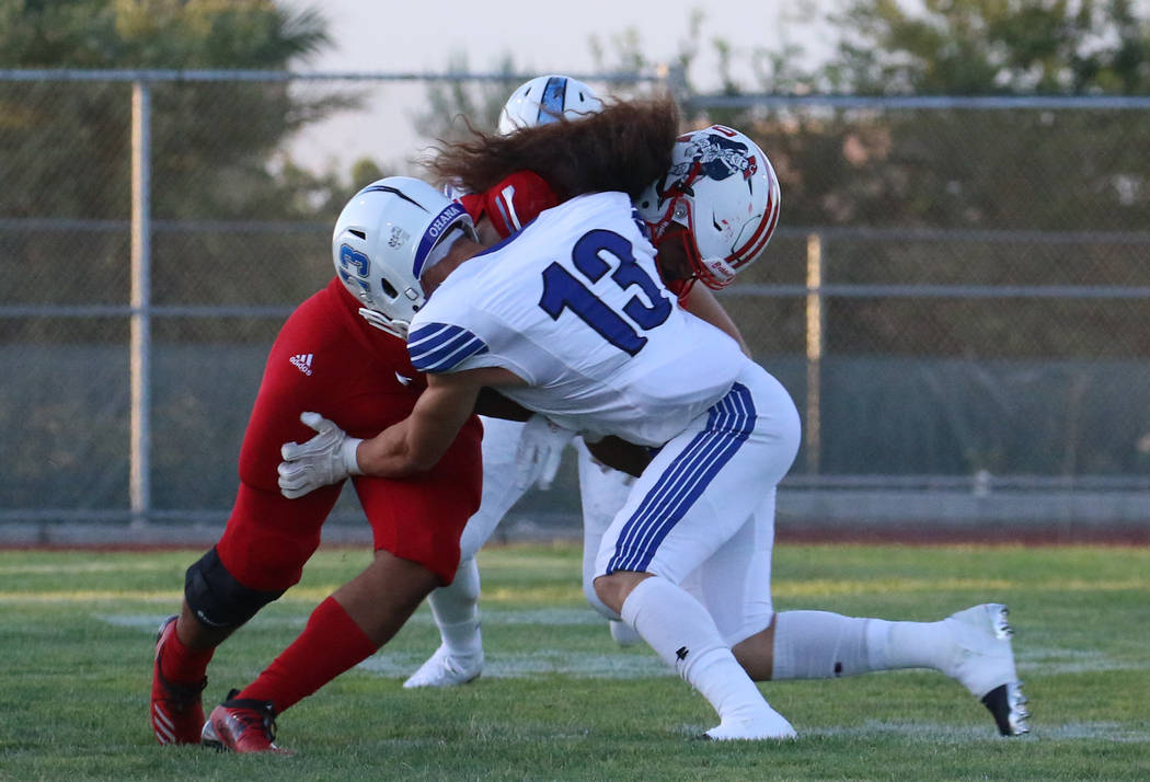 The Liberty High's Zyrus Fiaseu, left, protects the ball as he tackles Chandler, Ariz., High's ...