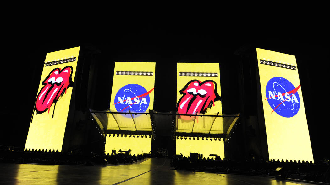 The logos for the band The Rolling Stones and NASA are displayed side-by-side on video monitors ...