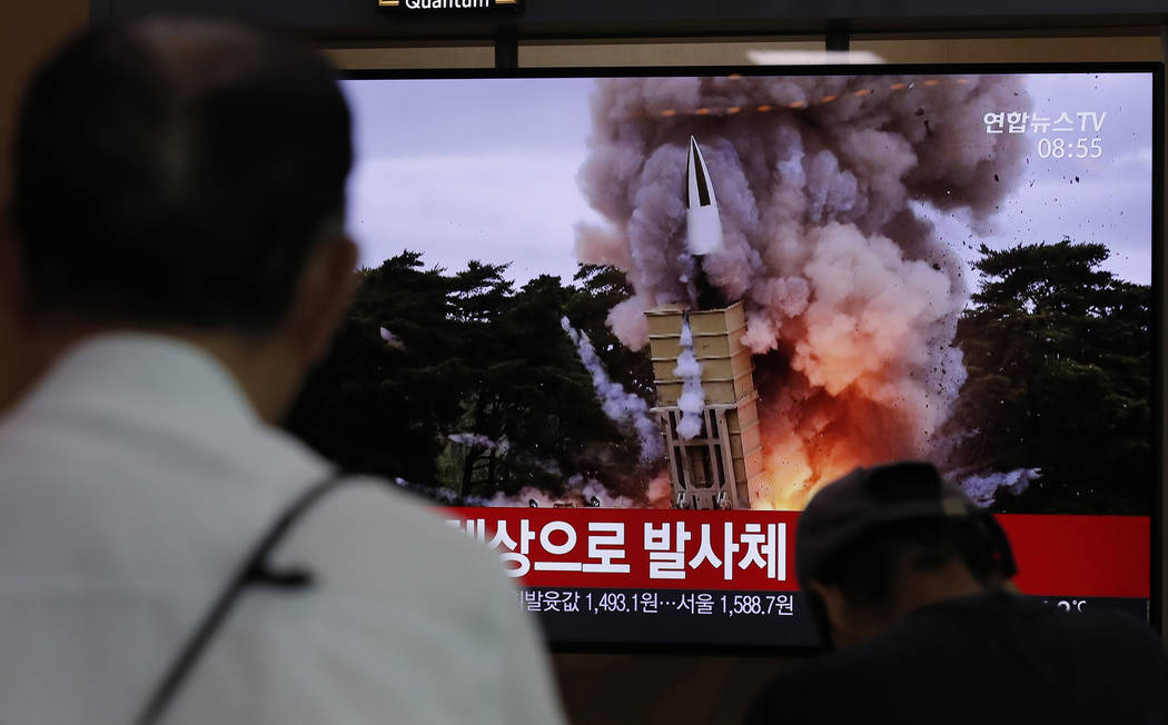 People watch a TV news program reporting North Korea's firing projectiles with a file image at ...