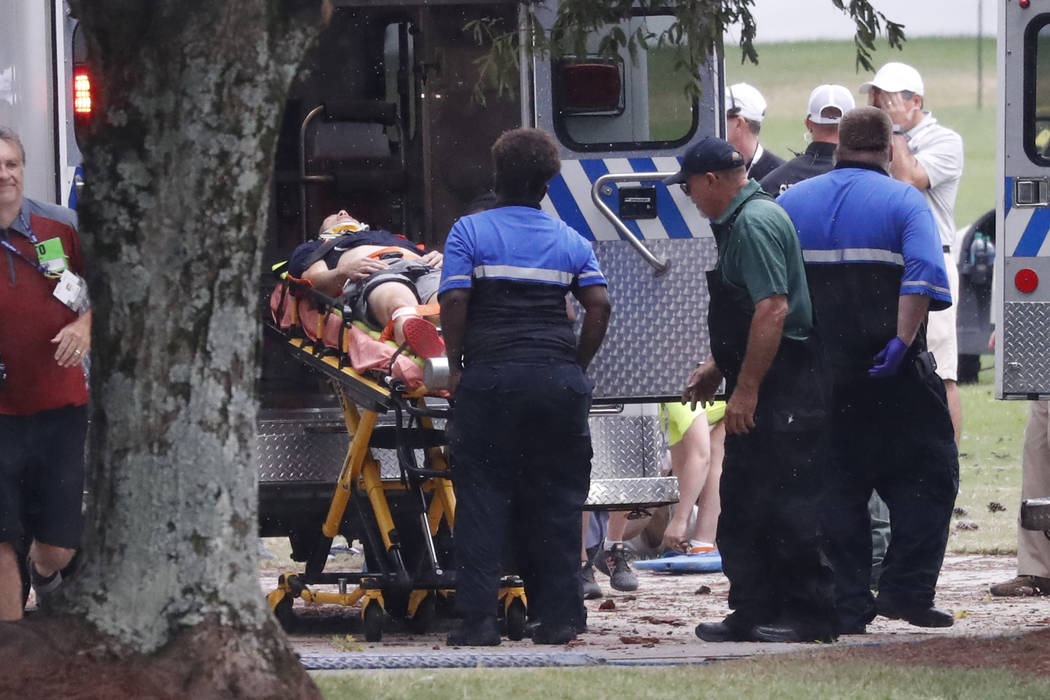 A injured golf fan is loaded into an ambulance after being struck lightning near the practice r ...