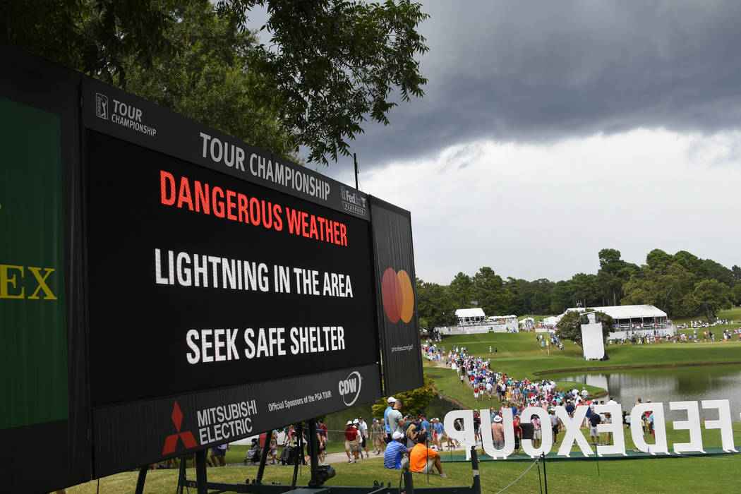 A sign warns of inclement weather as fans come off the course after a delay was called during t ...