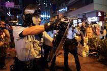 A policeman points a weapon during a protest in Hong Kong, Sunday, Aug. 25, 2019. Hong Kong pol ...