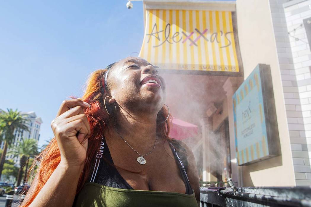 Shelle Ralph from North Carolina cools off from the heat in a water mist outside of Alexxa's Ba ...