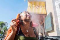 Shelle Ralph from North Carolina cools off from the heat in a water mist outside of Alexxa's Ba ...