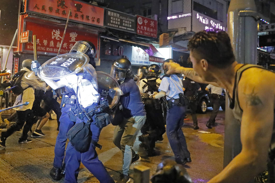 A man throws a brick to policemen on a street during a protest in Hong Kong, Sunday, Aug. 25, 2 ...