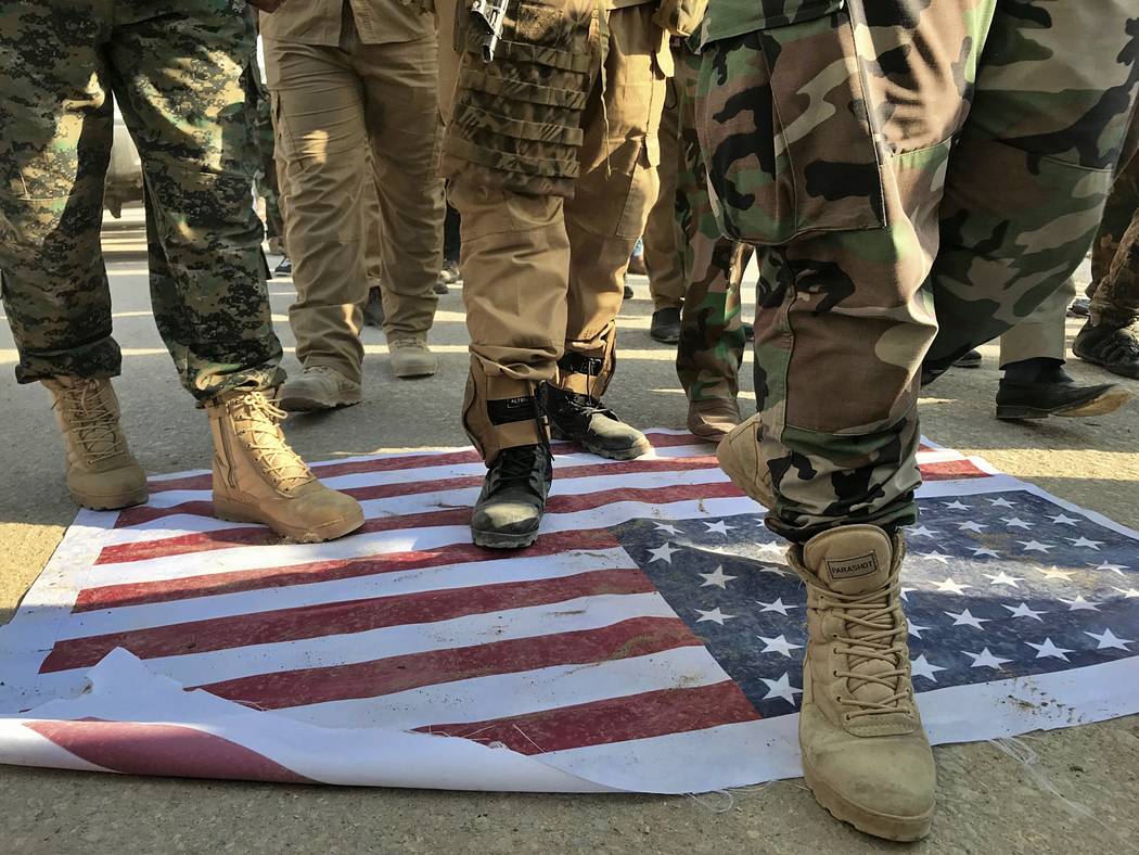 Mourners step over the print of a U.S. flag during the funeral procession of Abu Ali al-Dabi, a ...