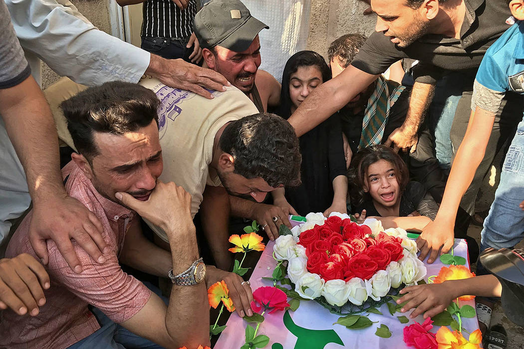 Mourners grieve at the coffin of Abu Ali al-Dabi, a fighter of the Popular Mobilization Forces ...