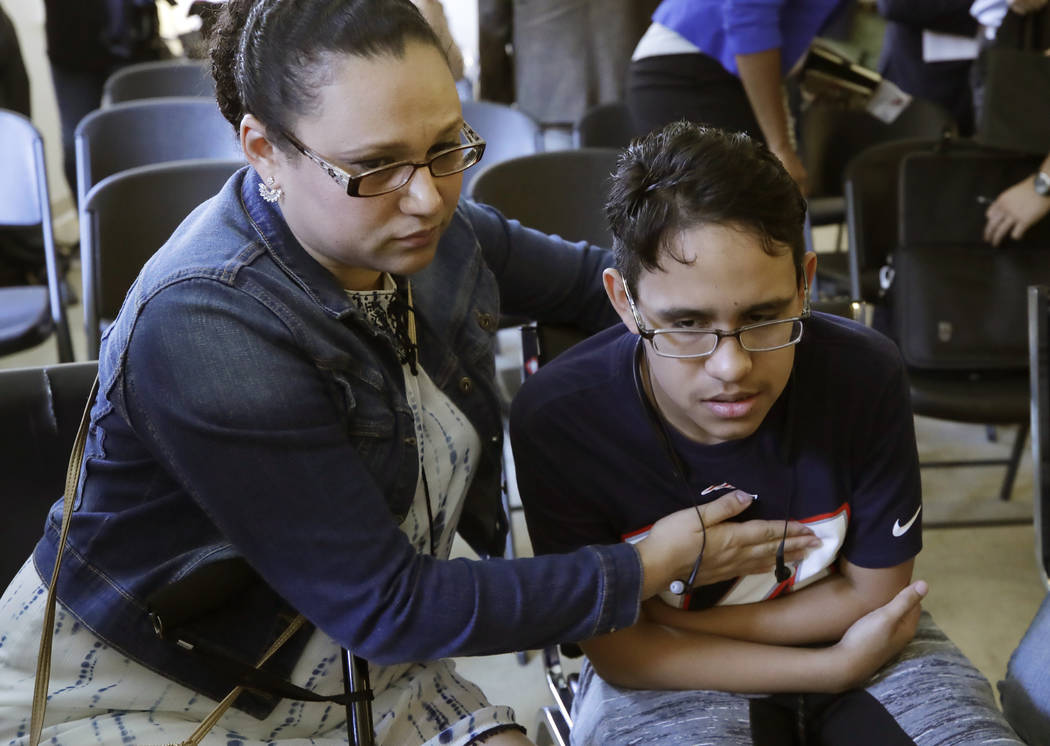 Mariela Sanchez, of Honduras, comforts her son, Jonathan, 16, during a news conference, Monday, ...