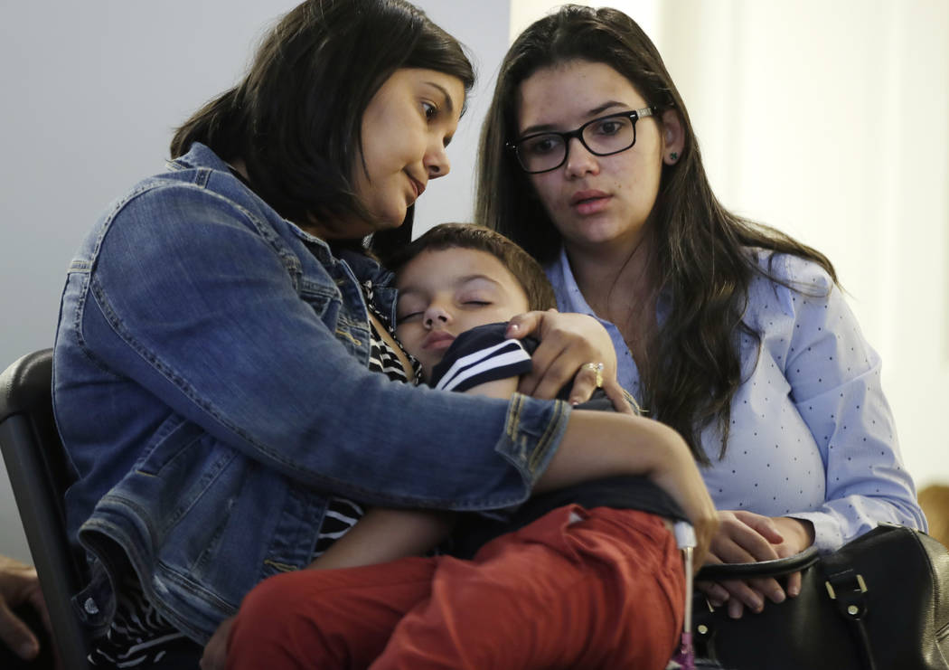 Sirlen Costa, of Brazil, holds her son Samuel, 5, as her niece Danyelle Sales, right, looks on ...