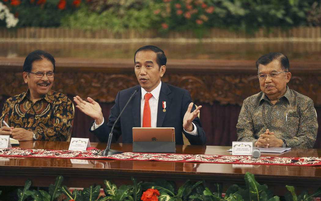 Indonesia President Joko Widodo, center, speaks as his deputy Jusuf Kalla, right, and Minister ...