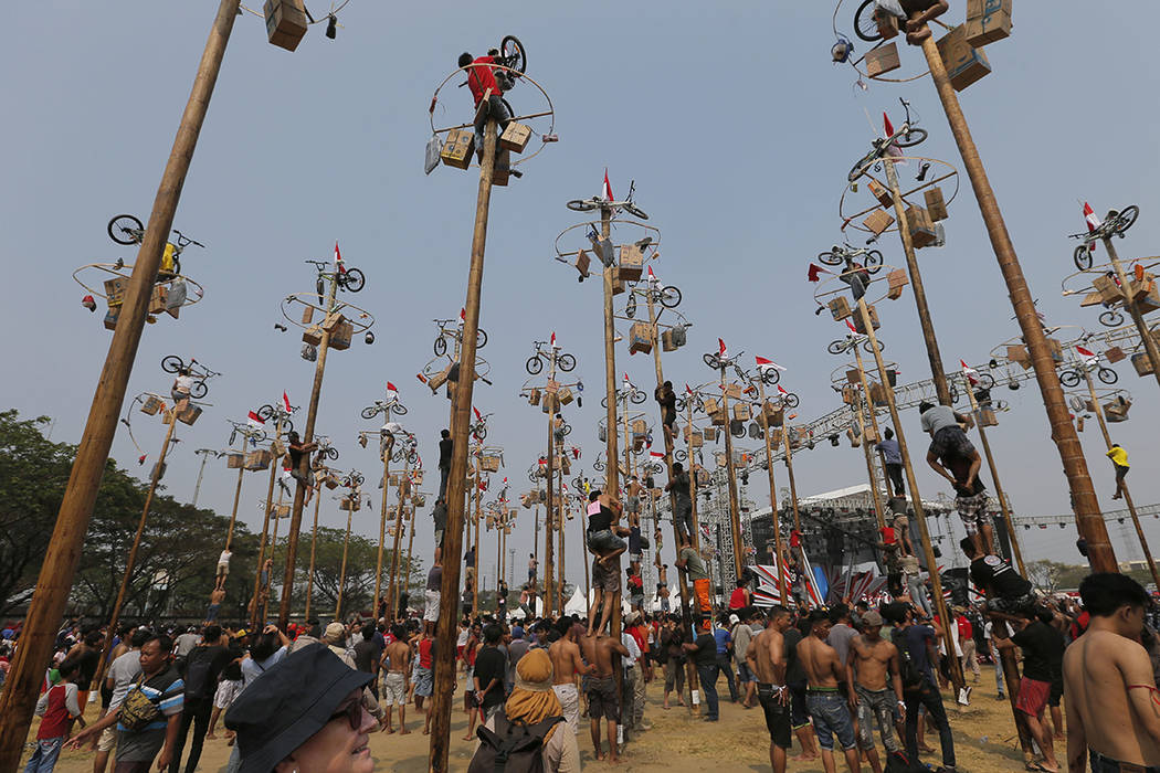 Participants struggle to reach the prizes during a greased-pole climbing competition held as pa ...