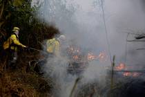 Firefighters work to put out fires along the road to Jacunda National Forest, near the city of ...