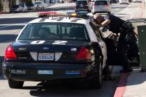 A Los Angeles Police Department officer talks to an occupant inside of his squad car. (Getty Im ...