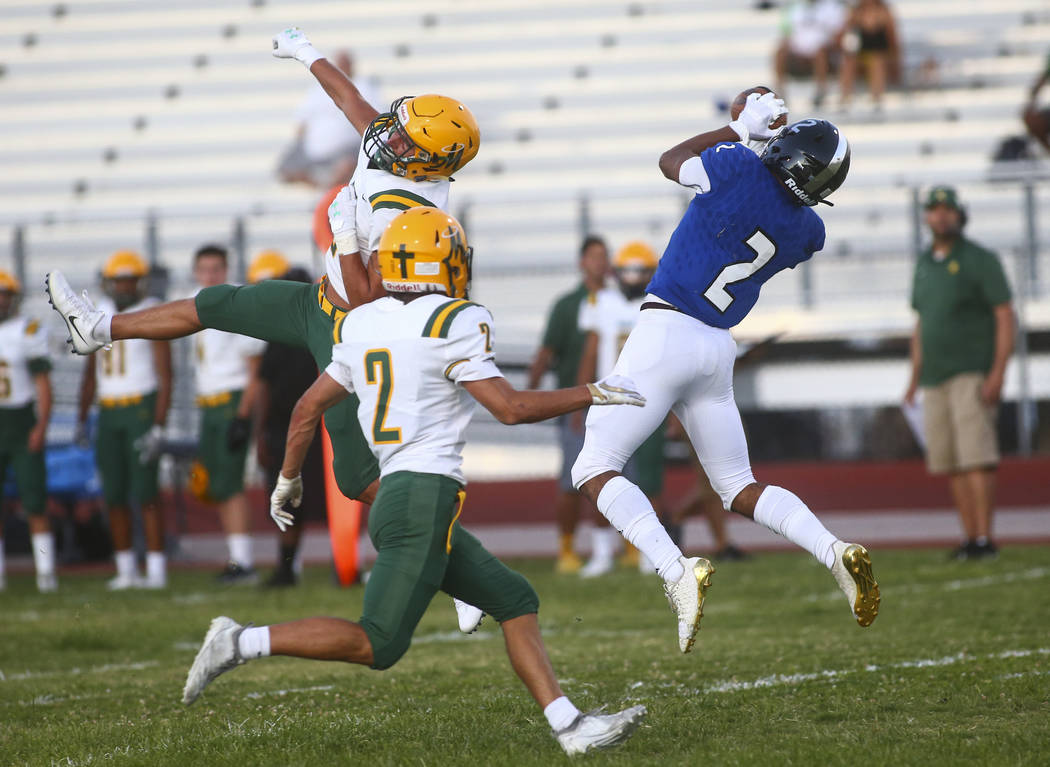 Desert Pines' Deandre Moore, right, catches a pass under pressure from Bishop Manogue's Mateo R ...