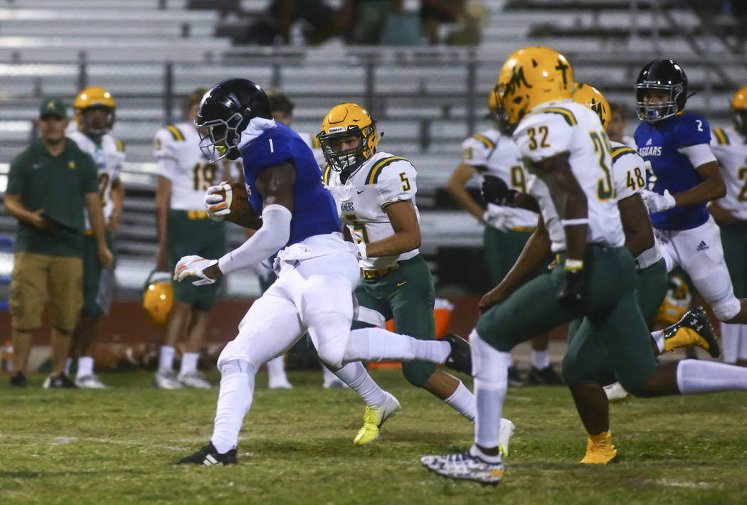 Desert Pines' Darnell Washington (1) runs the ball past Bishop Manogue's Jacob Romero (5) durin ...