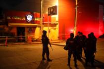 Police officers guard the scene outside a bar where more than 20 people died in an overnight at ...