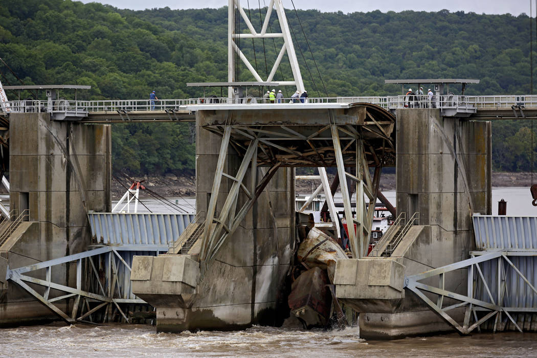 Workers attach cables and chains to one of two sunken barges at Webbers Falls Lock and Dam 16 a ...
