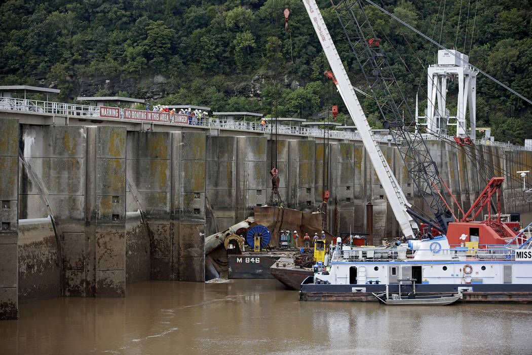 Workers attach cables and chains to one of two sunken barges at Webbers Falls Lock and Dam 16 a ...