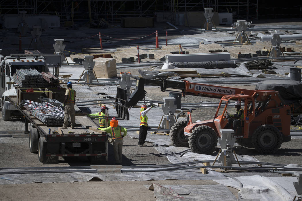 Workers move equipment from the floor level of the Raiders Allegiant Stadium construction site ...