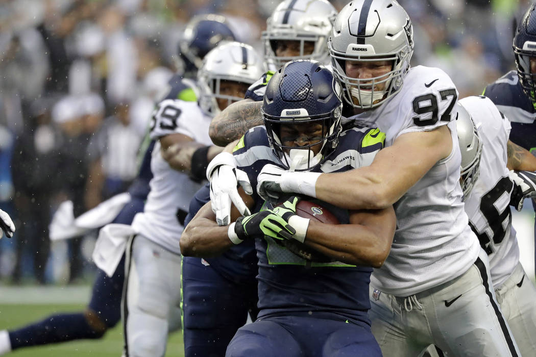 Seattle Seahawks running back C.J. Prosise, center, is tackled by Oakland Raiders defensive end ...