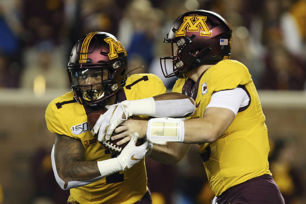 Minnesota quarterback Tanner Morgan, right, hands off the ball to running back Rodney Smith (1) ...