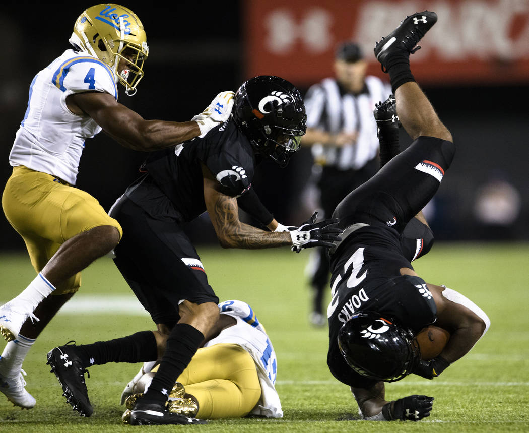 UCLA defensive back Elijah Gates (12) tackles Cincinnati running back Gerrid Doaks (23) during ...