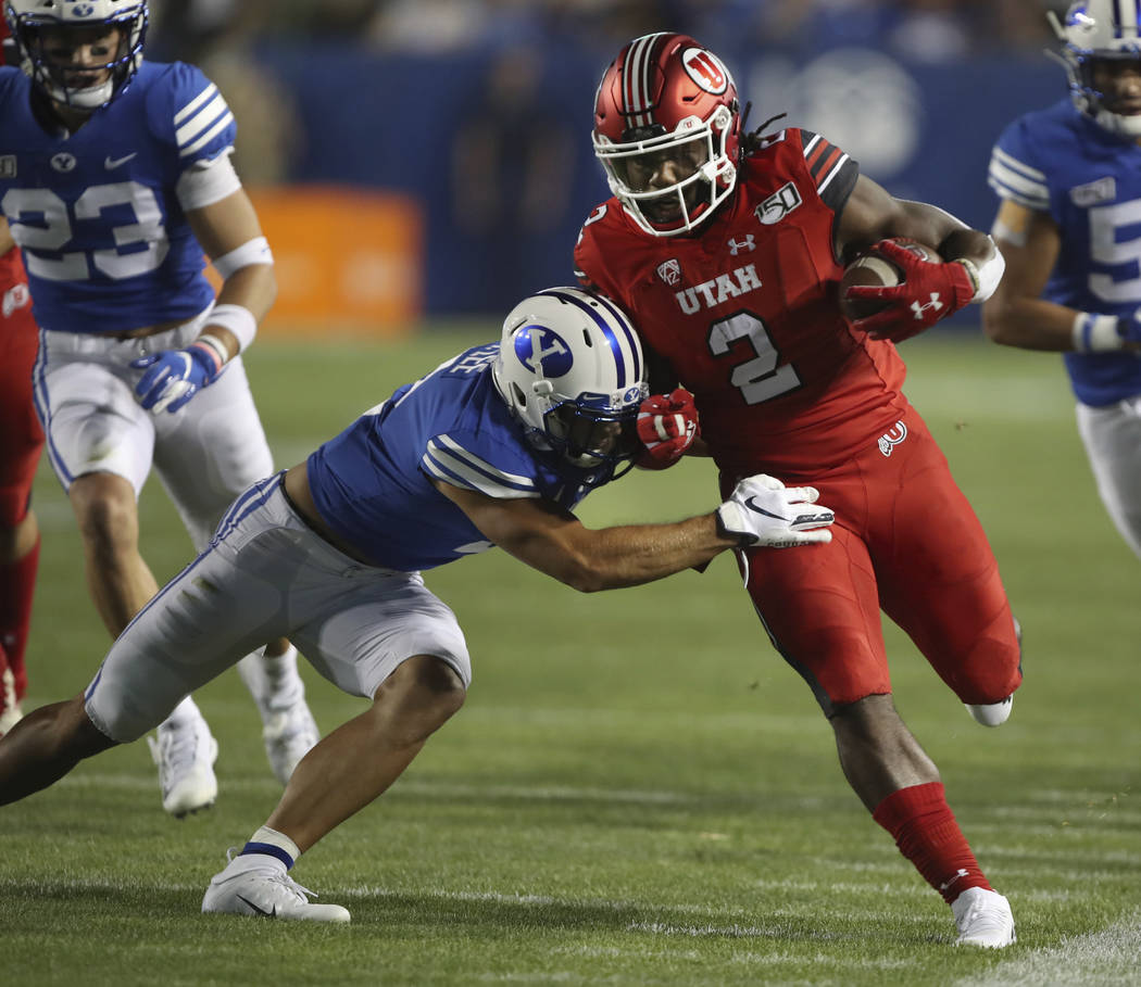Utah running back Zack Moss, right, is tackled by BYU defensive back Austin Lee during the firs ...