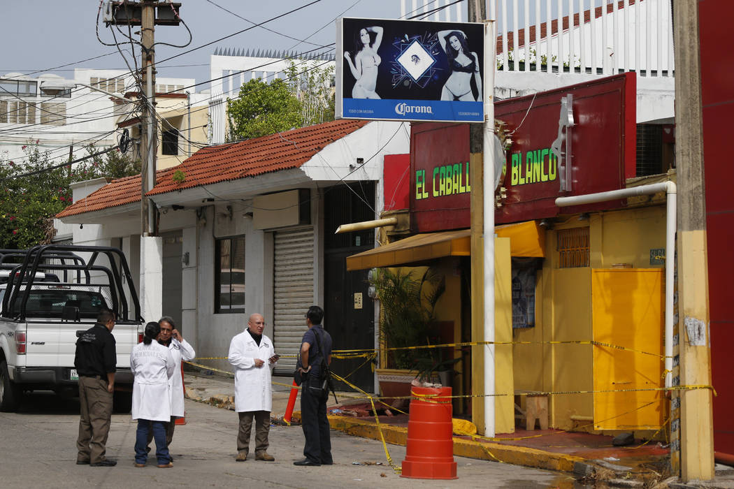 Investigators work outside the White Horse nightclub, the scene of a Tuesday night attack that ...