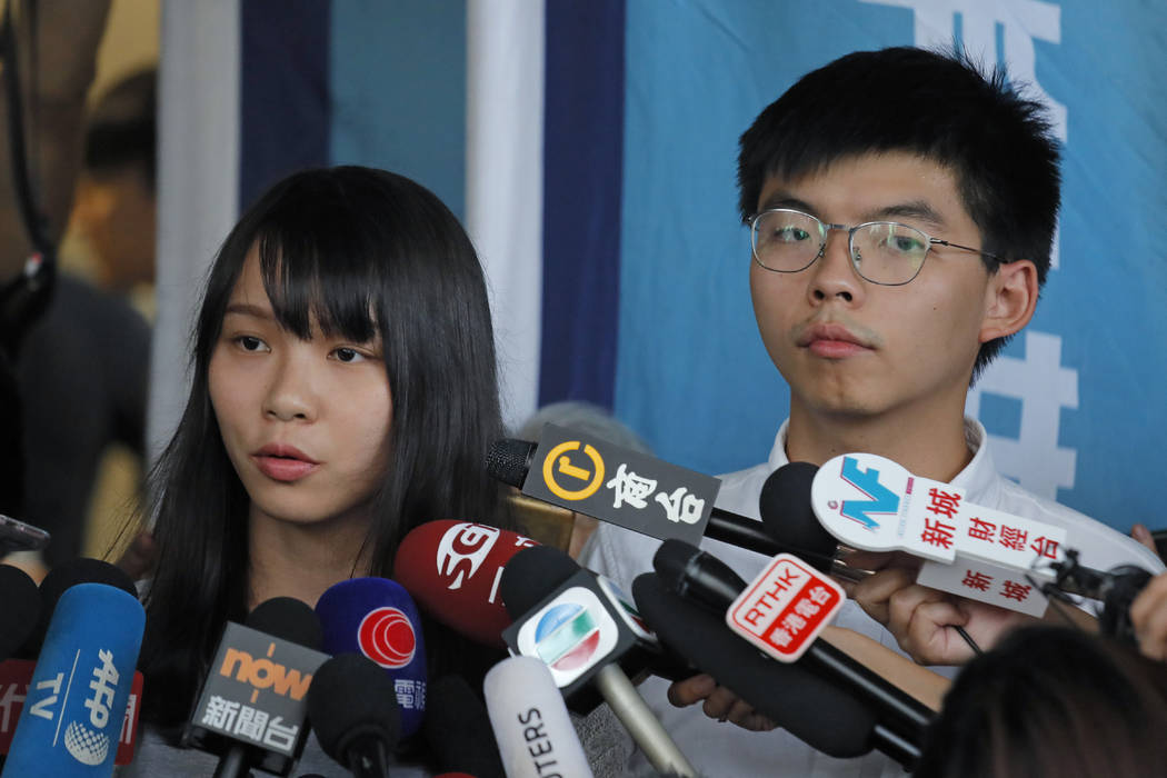 Pro-democracy activists Joshua Wong, right, and Agnes Chow speak to media outside a district co ...