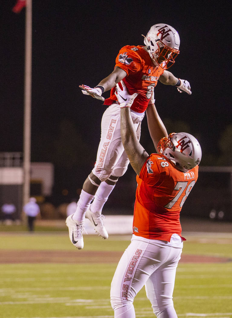 UNLV Rebels running back Charles Williams (8) is hoisted by UNLV Rebels offensive lineman Justi ...