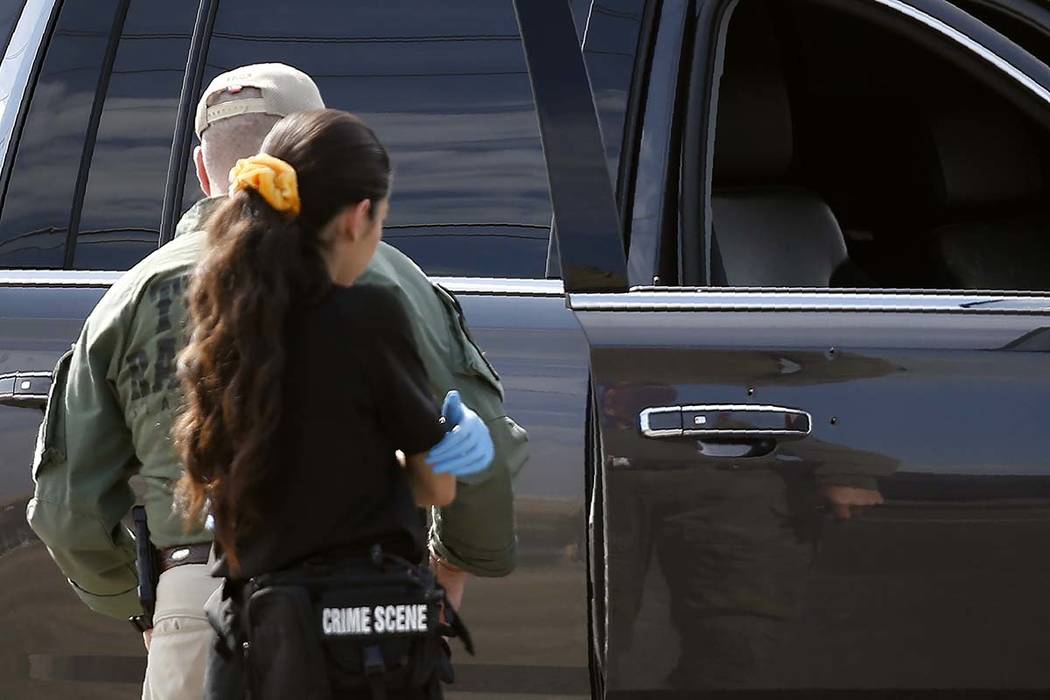 Bullet holes appear near a door handle of a car as law enforcement officials process a scene in ...
