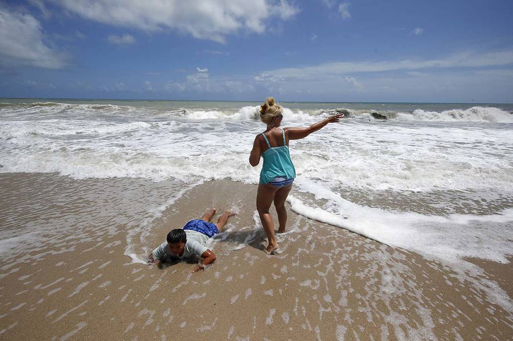 Tenille Choi and her son Remington Choi play in the high surf form the Atlantic Ocean on the ba ...