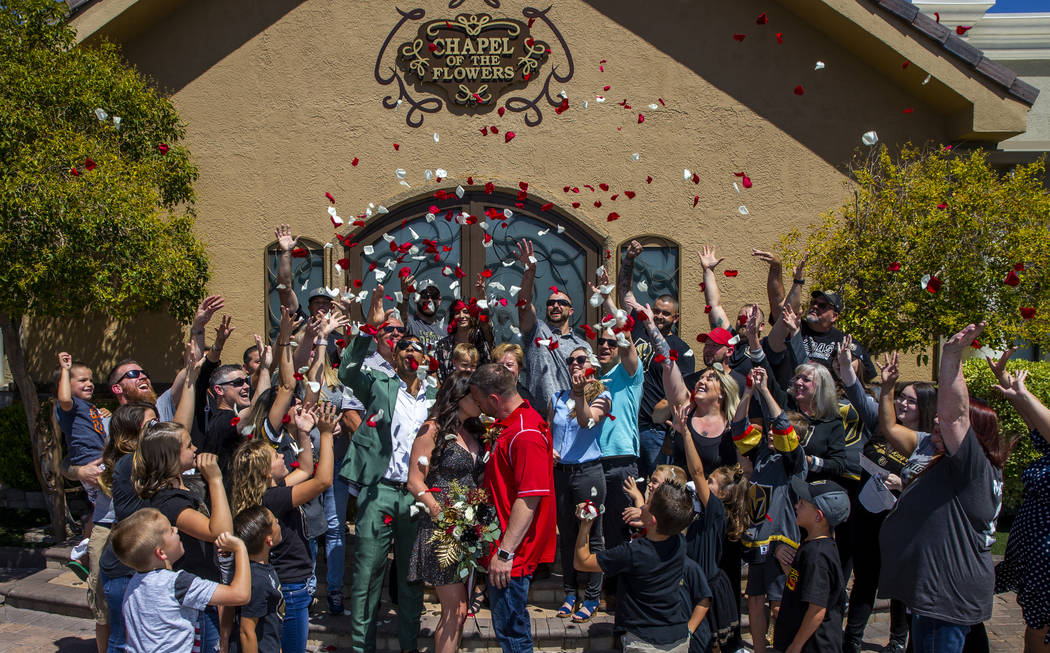 Guests toss flower petals as Laura and Justin Long kiss beside Vegas Golden Knights player Ryan ...