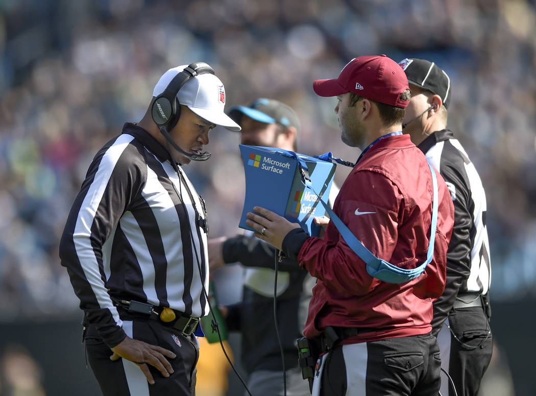 Referee Shawn Smith (14) reviews a play during the first half of an NFL football game between t ...