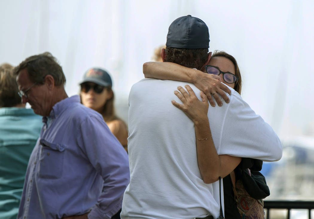 People hug each other as they await news outside of the Truth Aquatics office in Santa Barbara, ...
