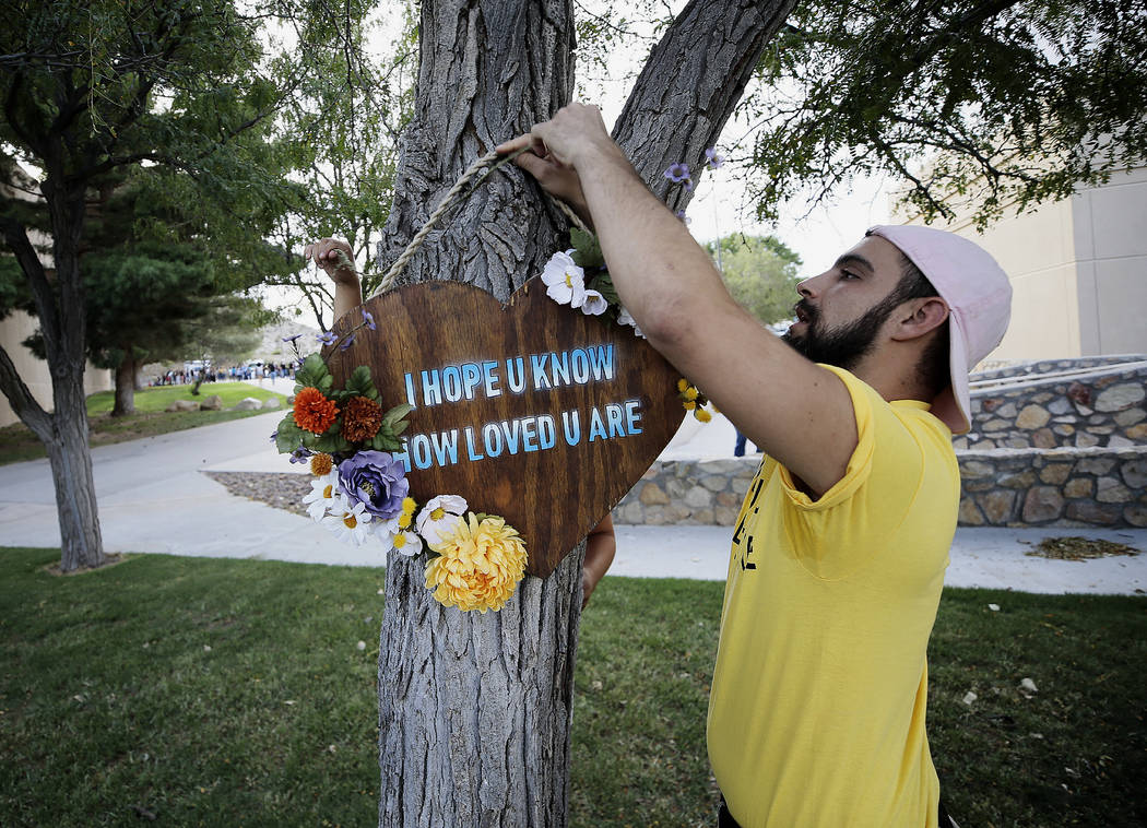 Los Angeles-based artists Noah Reich, right, and David Maldonado, behind the tree, hang a heart ...