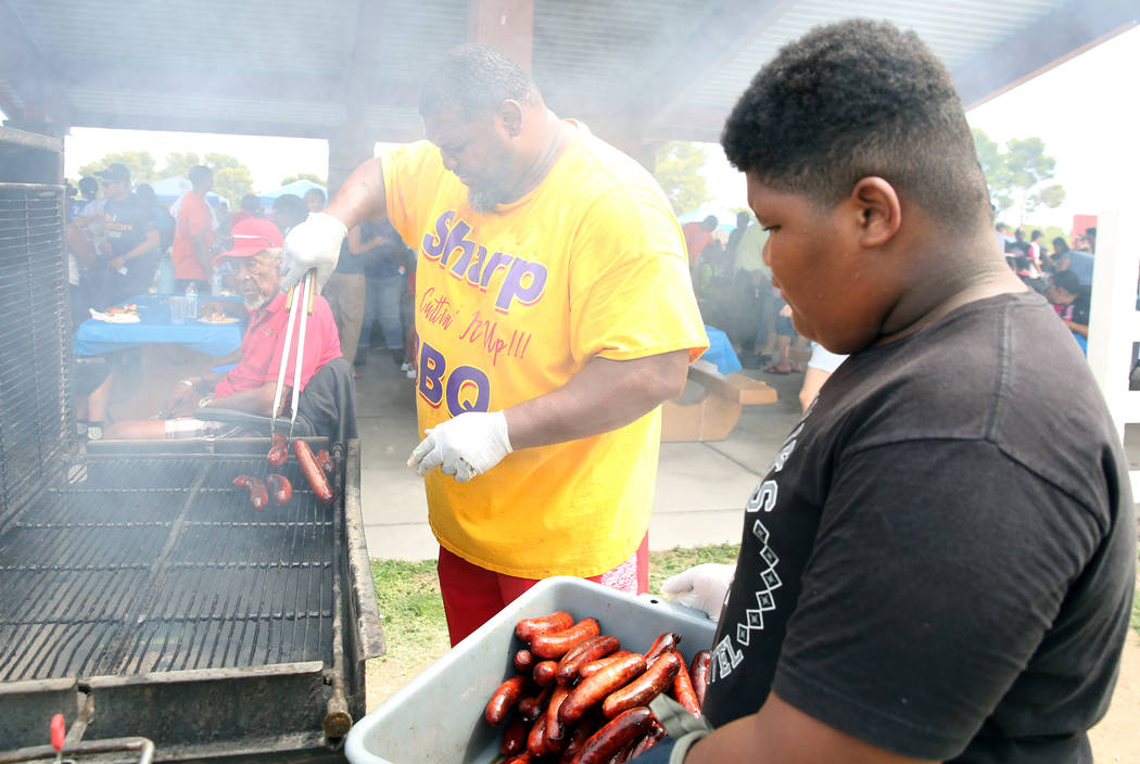 Jackie Stevenson, co-owner of Sharp BBQ, grills hotdogs as his son Jackie lll, 11, looks on dur ...