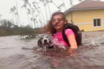 Julia Aylen wades through waist deep water carrying her pet dog as she is rescued from her floo ...