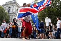 An anti Brexit protester waves the flags of European Union and Britain during a rally outside D ...