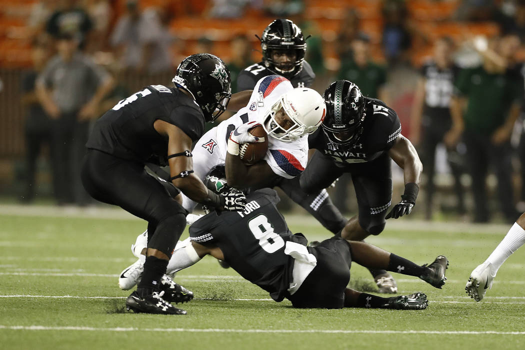 Arizona running back J.J. Taylor (21) tries to break through the Hawaii defense during an NCAA ...