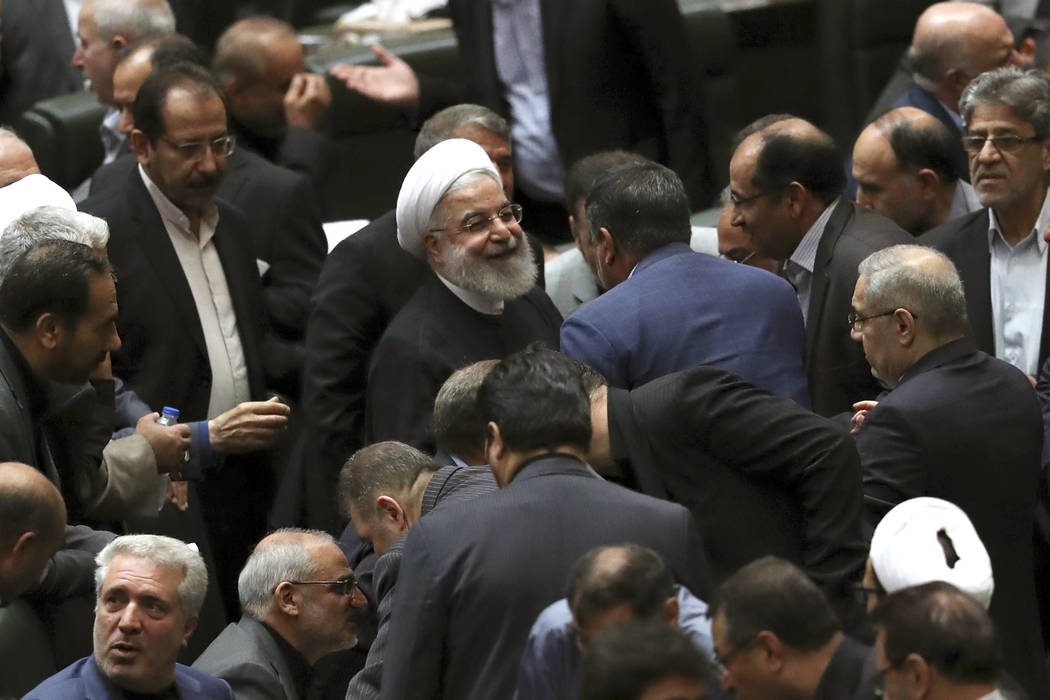 Iranian President Hassan Rouhani, center, listens to a lawmaker after defending his proposed to ...