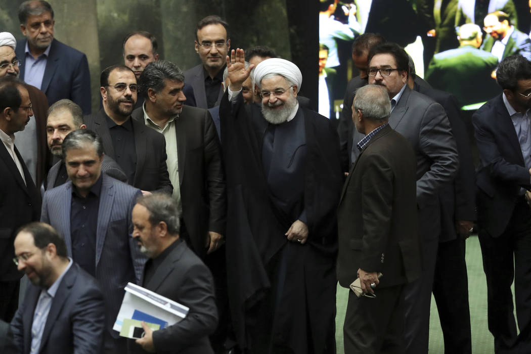 Iranian President Hassan Rouhani, center, waves to media as he arrives at the parliament to def ...