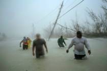Volunteers walk under the wind and rain from Hurricane Dorian through a flooded road as they wo ...