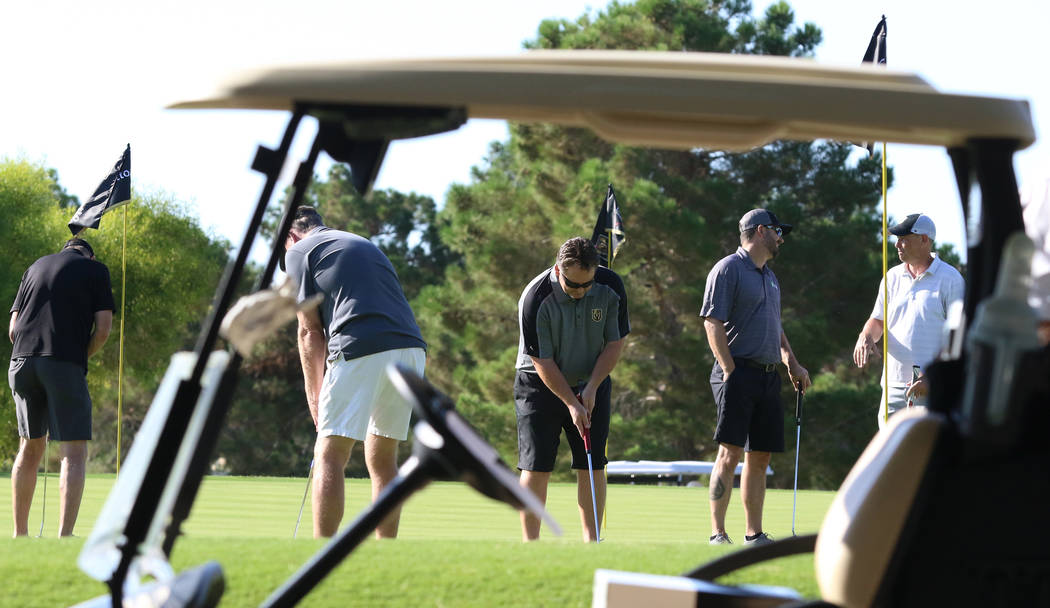 Participants practice putting during the Golden Knights charity golf tournament at TPC Summerli ...