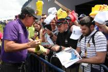 Phil Mickelson of the United States signs autographs on the 18th fairway during a practice roun ...
